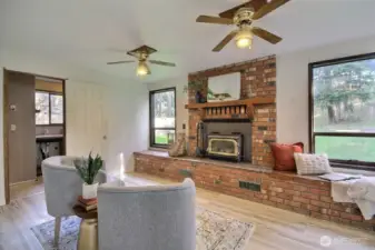 The open-concept living and dining areas flow seamlessly into a cozy family room, complete with brick fireplace and woodstove insert.