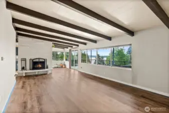 Large bright open living room with exposed wood beams and wood burning fireplace with stunning view of Dyes Inlet.