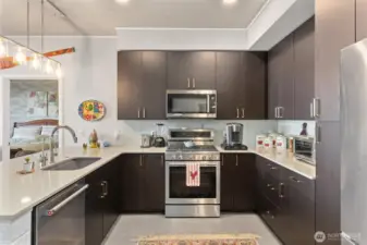 Gorgeous kitchen with modern finishes, 6-burner gas stove, glass tile backsplash, quartz countertops and eating bar. Notice the custom accent tile on the end of the countertop and the ceilings!