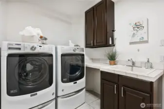 Full laundry room with utility sink and custom storage cabinets.