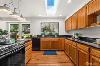 A skylight brightens the kitchen area, featuring solid wood flooring and cabinetry.