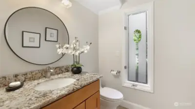 The powder room has a granite counter and white enamel touches.