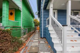 Walkway on the side of the home leads to the back door for the home, private entrance for the basement, and to the units that will be behind the fence.