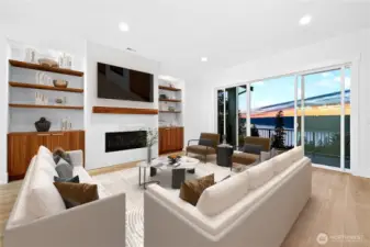 Spacious living room featuring a gas fireplace with plenty of built-in shelving and storage, perfect for entertaining or everyday living. Enjoy sweeping Lake Sammamish views through large sliding glass doors that open to the main-level wraparound deck.