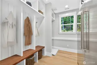 Mudroom off the garage features coat racks, a bench with under-seat storage, washer/dryer hookups, and a large high-end fridge. A bright window brings in natural light while maintaining privacy, and a cozy corner nook could serve as a pet area. Let you imagination run wild!