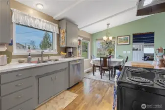 This view shows Light and bright refreshed kitchen with dining area and box beam ceilings. Doorway to the left leads to family room and garage with an exterior door.