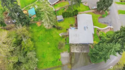 This aerial shot shows huge drive way, RV parking behind fence, outdoor storage shed and in front of home is guest parking.Property goes back to tree line.