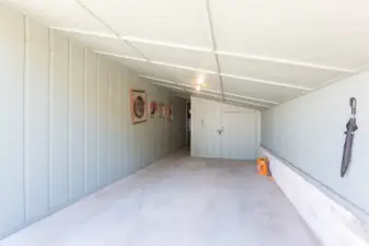 Carport - There is a storage room with shelves at the back.