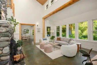 The living room is lined with gorgeous divided-light windows, and offers views of more flower beds, the pond, the meadows, and the forest beyond. Polished concrete floors, peeled posts, and wood-paneled ceilings combine to lend the feel of an elevated country house.
