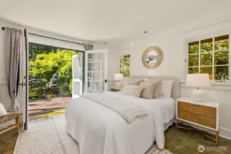 The primary suite’s cozy sleeping space opens to a paved patio with glorious views of the landscaping and pond.