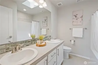 Central to all three bedrooms is the full guest bathroom with dual vanity sinks, tiled flooring, tiled backsplash and a bonus skylight for even more natural light.