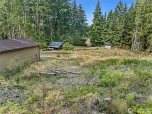 West facing view. Shop (left), carport, outbuilding with pressure tank (right) and Mace Lake across the street.