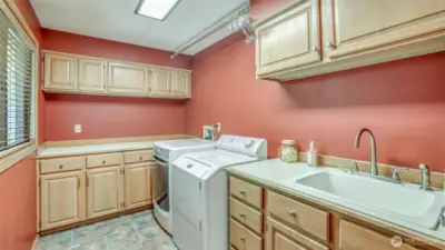 Organized laundry space designed with plenty of cabinetry, counter space, and a utility sink for added convenience.
