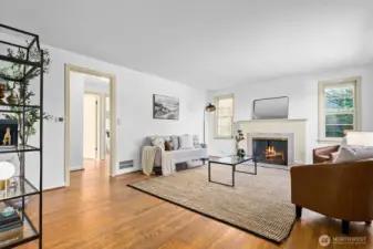 Enter to the light filled living room with hardwood floors, wood paine windows and charming fireplace
