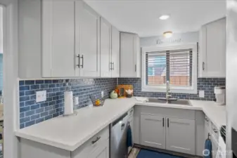 Remodeled kitchen featuring quartz countertops, shaker cabinetry, and a striking navy tile backsplash.