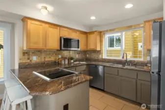 Kitchen with breakfast bar with Maple cabinets designer tile backsplash and granite counters.