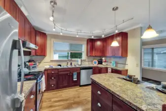 Custom lighting in this light and open kitchen. Garden window above the double stainless-steel sink. Tile splash back is another modern feature.