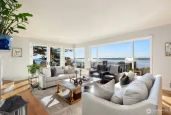 Entertain effortlessly in the formal dining room and spacious living room with gas fireplace and wood-planked top-nail hardwoods. French doors open to a view deck—perfect for sunset dinners—while expansive windows frame breathtaking water and mountain vistas from nearly every room.