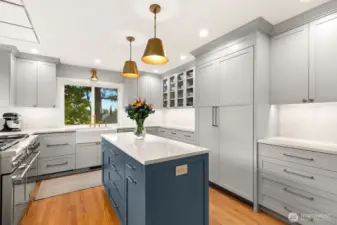 A stunning kitchen featuring custom cabinetry, stainless steel appliances, quartz countertops, and a charming built-in bench seating dining nook.