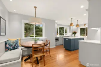 A stunning kitchen featuring custom cabinetry, stainless steel appliances, quartz countertops, and a charming built-in bench seating dining nook.