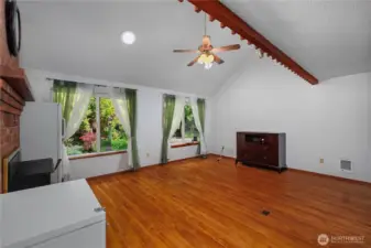 Open Great room with vaulted ceiling, fireplace and ceiling fan.