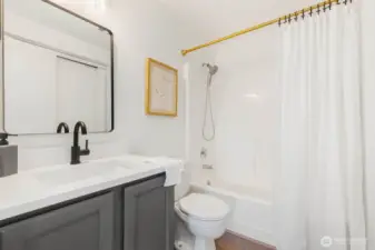 This crisp and clean bathroom features a new vanity counter, matte black fixtures, stylish lighting, and fresh trim—all complemented by neutral tones and timeless finishes.