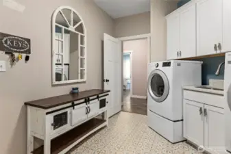Large laundry/mud room with deep sink & access through to primary bedroom