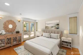 Primary bedroom with en-suite bath and French doors leading to the covered view patio. This image has been virtually staged.