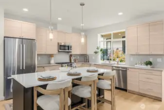 Chef’s kitchen with quartz countertops, premium stainless steel appliances, and a generous breakfast bar. (photos of model home)