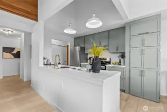 Custom, remodeled kitchen with quartz countertops, sage-green cabinetry, scalloped ceramic tiles, stainless steel appliances.