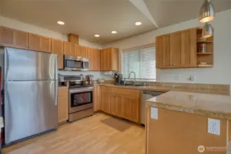 The kitchen is well appointed with stainless steel appliances, quartz tile countertops, and shaker cabinets.