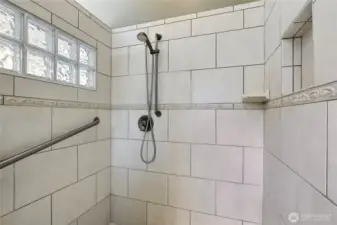 Primary bath shower, love the tile and glass block, I could stand here all day! Convenient built-ins.