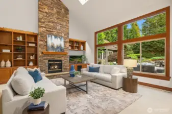 Two story family room with floor-to-ceiling stone fireplace, custom built-in cabinetry, and look at that wall of windows!