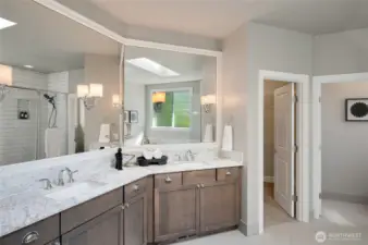 Primary en suite with spacious double sink vanity, a wall of mirrors, and designer quartz countertops.