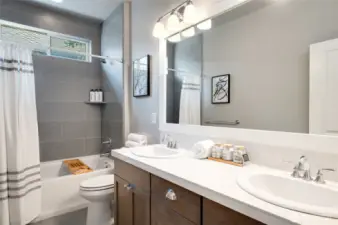 Full bathroom on the upper level with dual sink vanity and tile wrapped bath/shower.