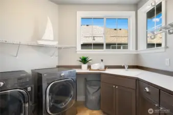 Jaw dropping Laundry Master's dream laundry room with utility sink, built-in cabinets, and countertop space for laundry prep.