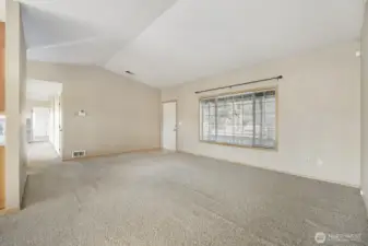 The spacious living room showing the front door and the vaulted ceiling.