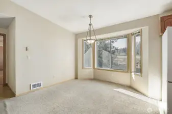 The dining area features a bay window and vaulted ceiling. The hallway to the left leads to the primary bedroom and the garage.