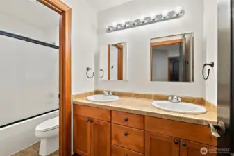 Secondary bathroom on the upper floor with separate shower area and dual sinks. Medicine cabinet mirrors for extra storage