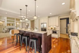 View of the great room, gourmet kitchen, and mudroom leading to the garage and laundry on the right. A walk-in pantry is to the left of the fridge.