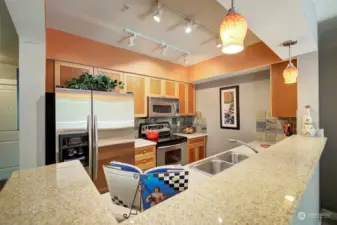 Granite bar space frames your fully equipped kitchen where all appliances stay with the home.