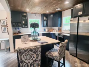 Spacious kitchen with an eat-in island, gorgeous farm sink,  and tons of cabinetry for all your cooking and storage needs.  All dishware and utensils to convey with the home.