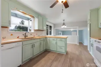 Bright kitchen with lots of light, butcher block counters, and soothing sage green cabinets.