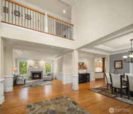 High ceilings above the foyer. The nice living room to the left side with gas fireplace, hardwood floors, and windows looking into the backyard. Dining room to the right side.