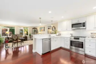 The gourmet kitchen is designed with entertaining in mind and features quartz counters with designer tile back splash, painted cabinets, high-end stainless appliances w/gas cooktop, bar top seating, and opens to the spacious living and dining rooms