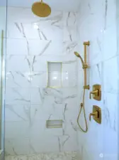 The custom tile shower boasts brushed brass finishes and convenient shower niches.