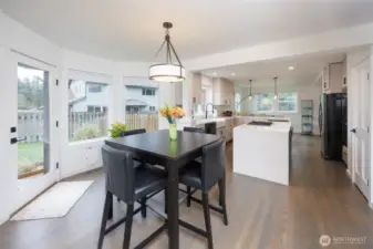 Eating area between kitchen and family room has a door to the fully fenced backyard with patio.