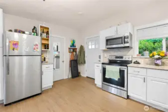 Open kitchen with stainless appliances, vinyl plank floors
