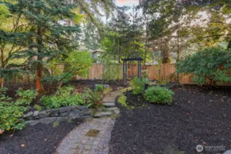 Admire the native NW plants and a winding path which leads to a trellis and the back of the yard.