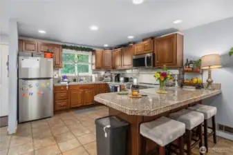Unit 2 – Spacious Kitchen Layout  Bright and functional kitchen in Unit 2 featuring an open layout with an abundance of cabinet storage, durable tile flooring, and recessed lighting. Granite-style counters provide plenty of prep space for everyday cooking or entertaining.